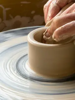 Manos dando forma a un cuenco de arcilla sobre el torno