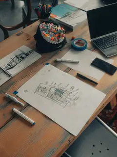 Mesa de trabajo con un plano dibujado y rotuladores