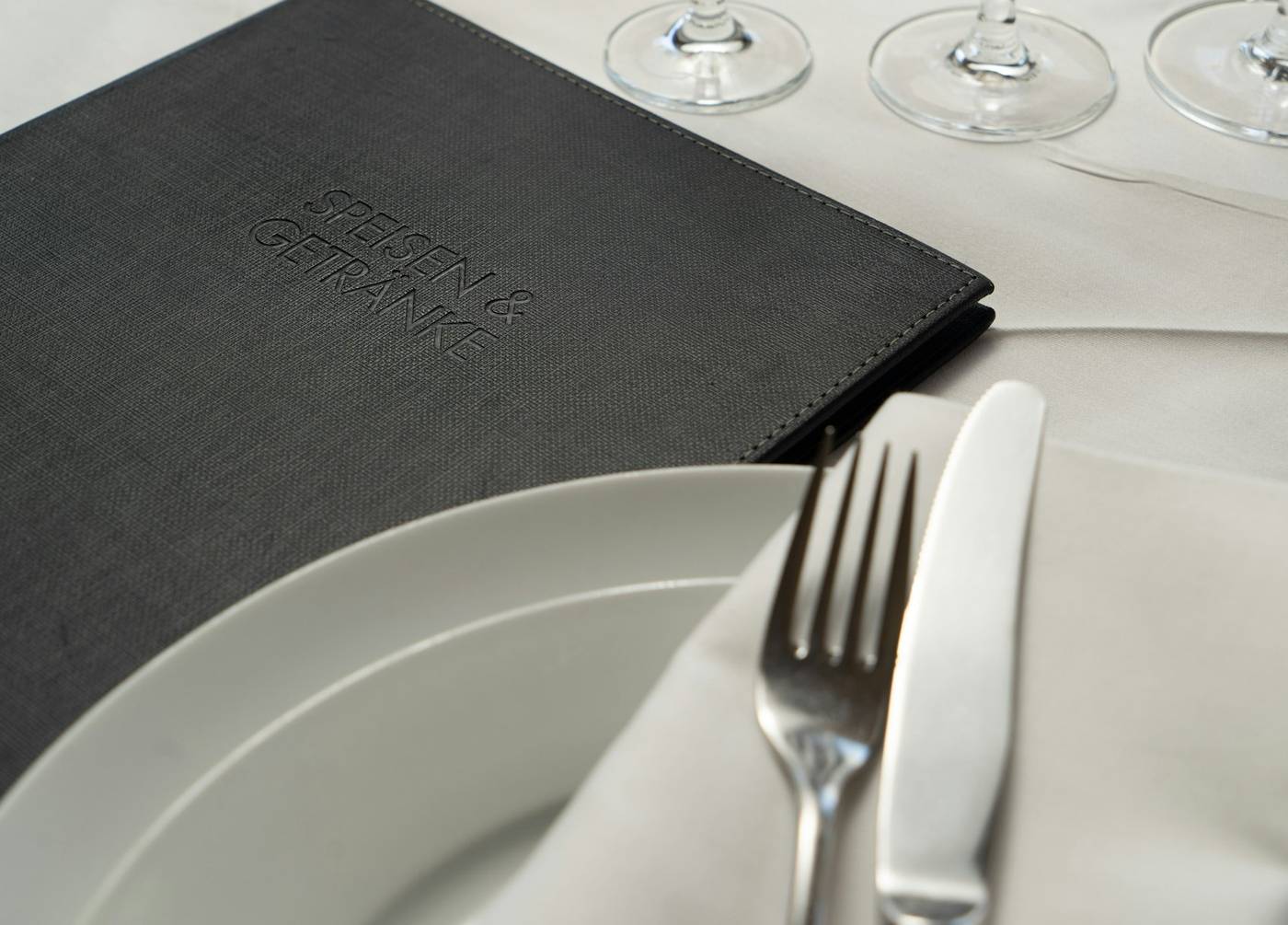 Carta negra sobre una mesa puesta, junto a un plato y un tenedor