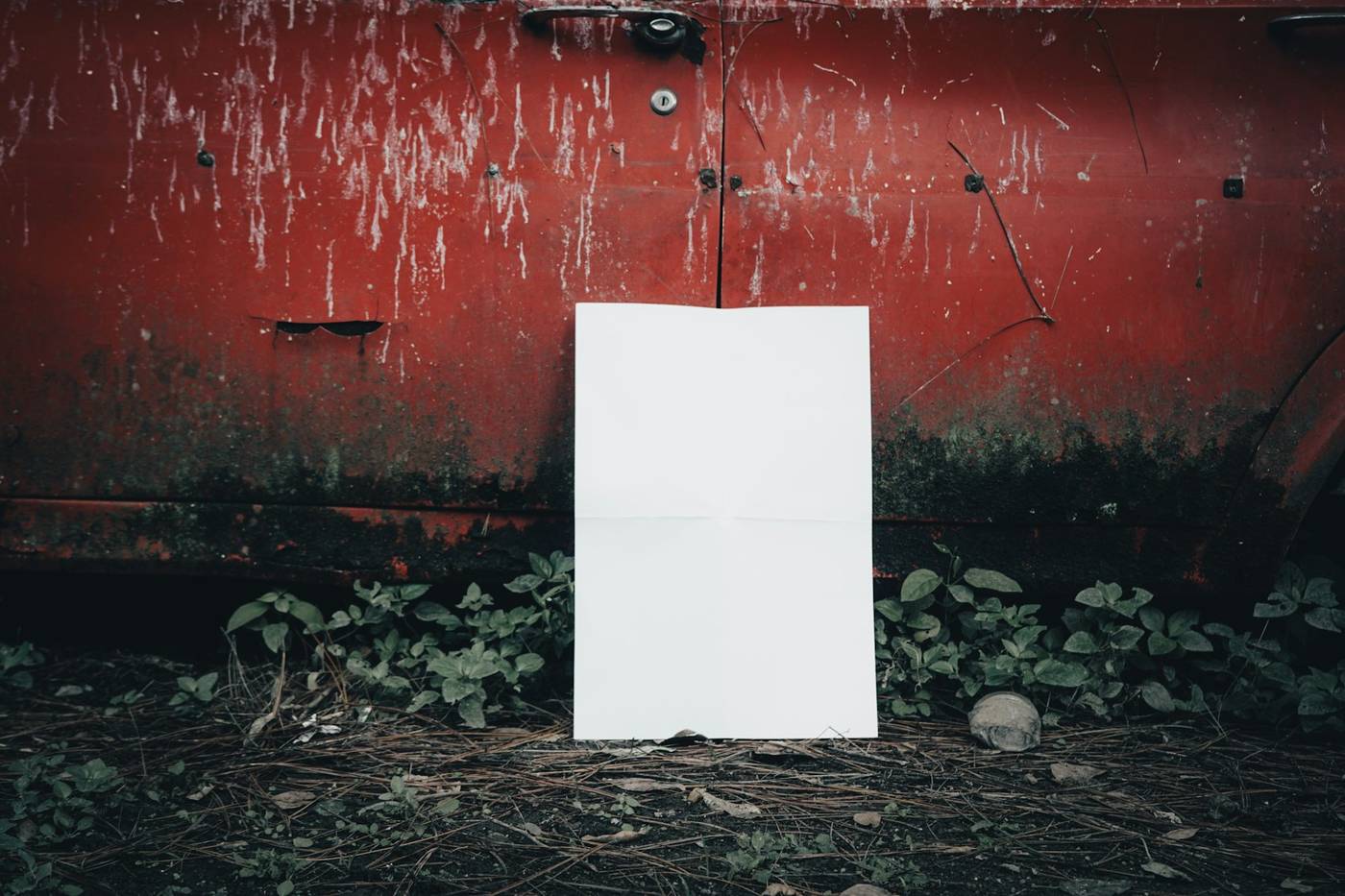 Hoja de papel blanca pegada en una pared roja desgastada