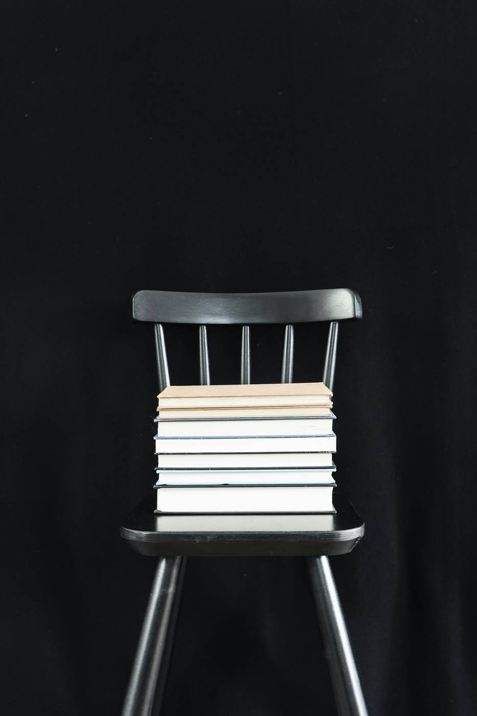 Pila de libros sobre una silla de madera, con fondo negro