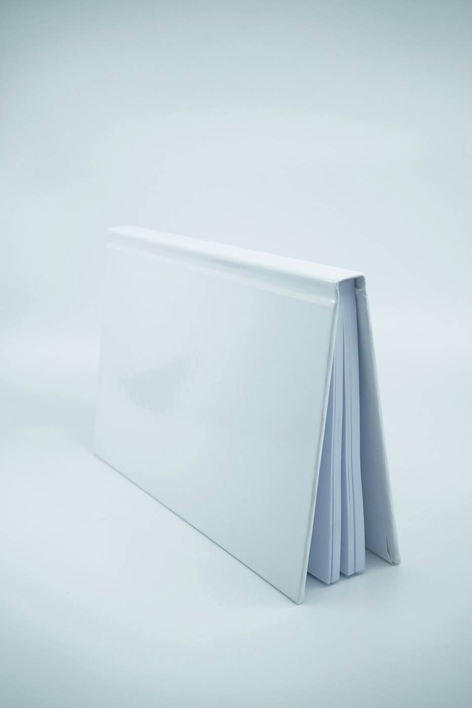 Libro de tapa blanca, sin título, de pie sobre una mesa blanca