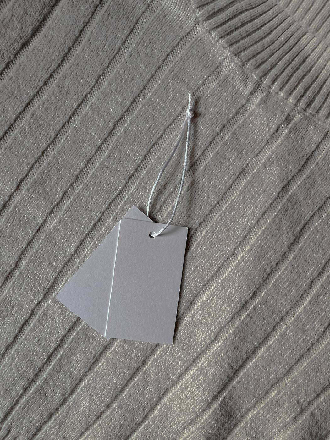Etiqueta gris colgada de un tejido acanalado
