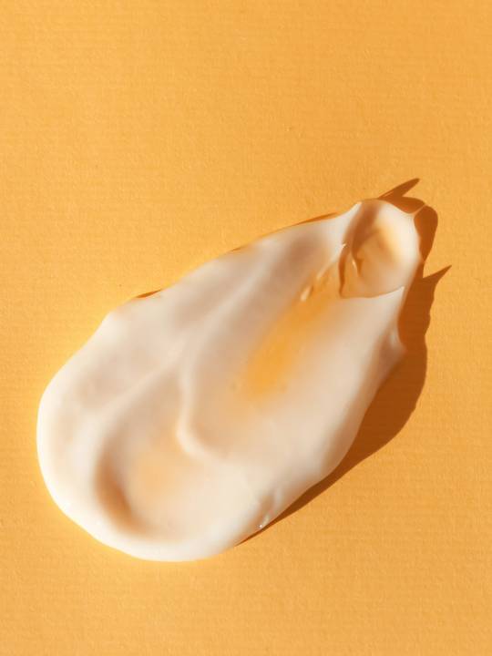 Una pincelada de crema blanca sobre papel naranja