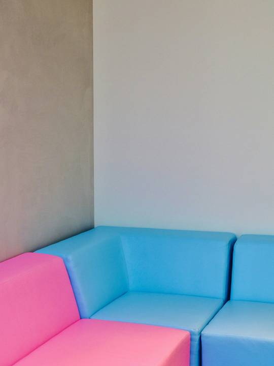 Sofá modular rosado y celeste junto a un muro beige