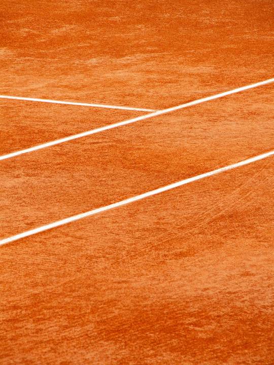 Cancha de arcilla anaranjada con líneas blancas