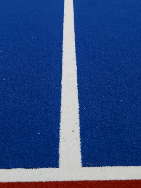 Pista de atletismo azul y roja con una línea blanca, de muy cerca