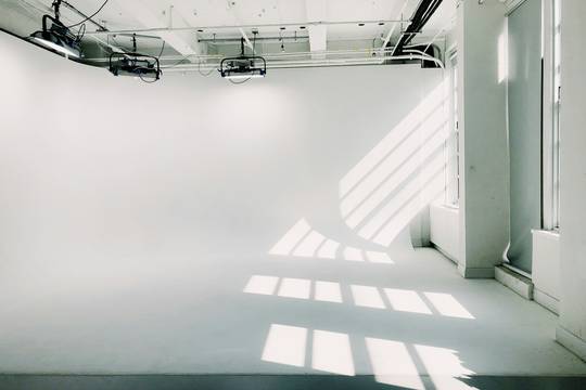 Estudio blanco con ventanales y luz sobre el piso