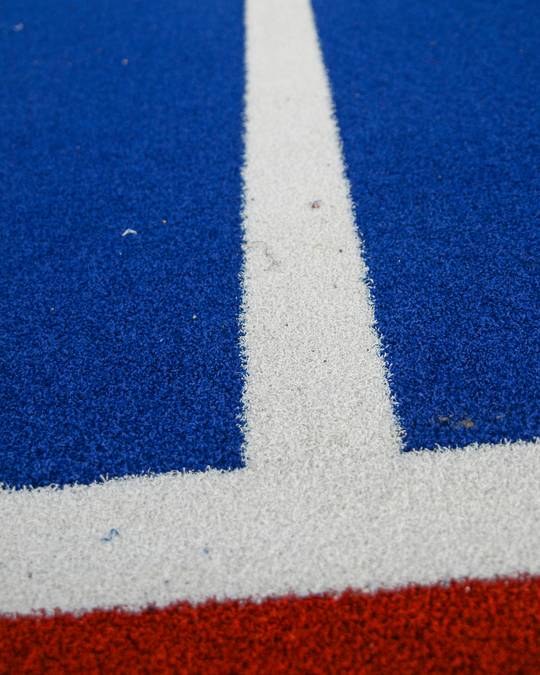 Pista de atletismo roja y azul con líneas blancas