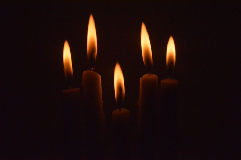 Cinco llamas encendidas sobre velas cortas en un cuarto oscuro