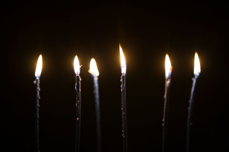 Seis llamas sobre velas delgadas y oscuras, en un cuarto sin otra luz