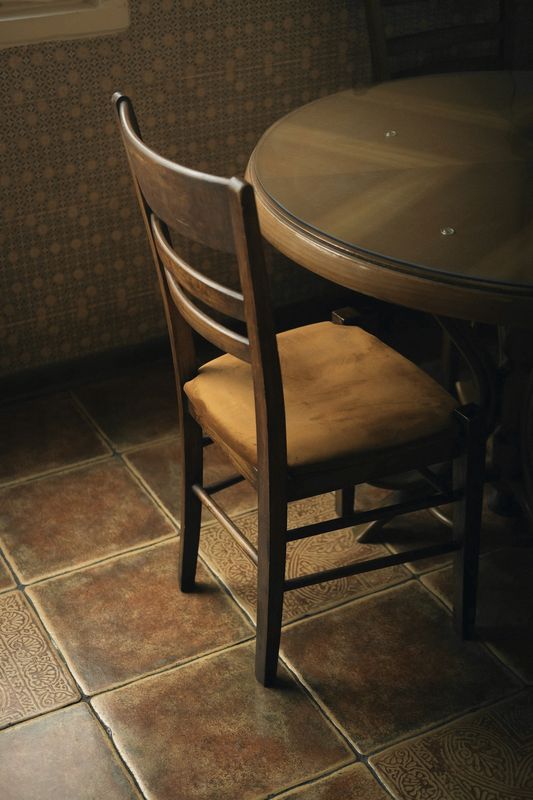 Silla de madera junto a una mesa redonda, sobre un piso de baldosas antiguas
