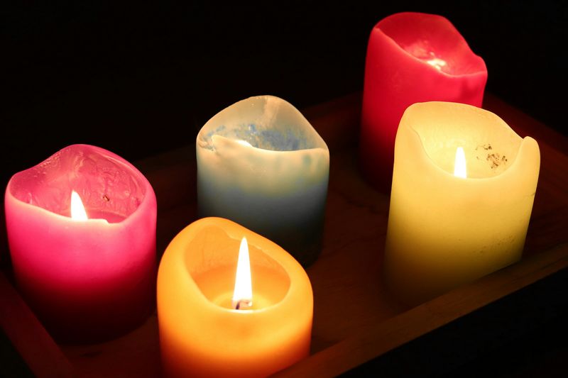 Cinco velas encendidas de colores sobre una bandeja de madera
