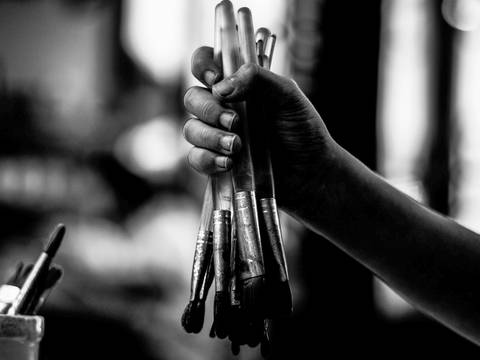 Una mano sostiene un manojo de pinceles en blanco y negro