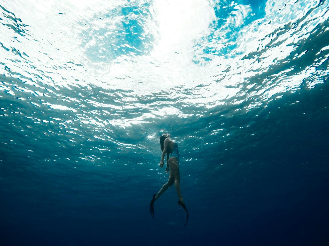 Nadadora bajo la superficie brillante del mar