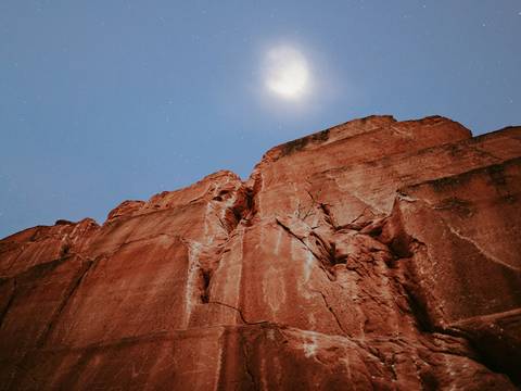 Luna llena sobre un farallón de roca roja al atardecer