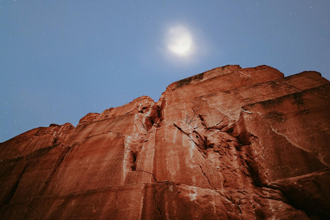 Luna llena sobre un farallón de roca roja al atardecer