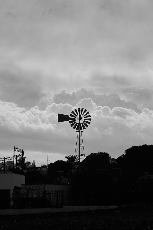 Silueta de un molino de viento contra un cielo cargado, en blanco y negro