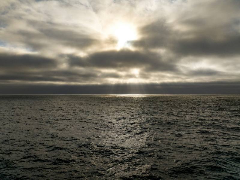 Sol velado entre nubes sobre el mar