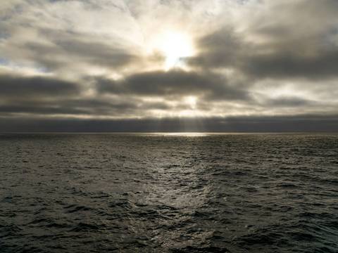Sol velado entre nubes sobre el mar