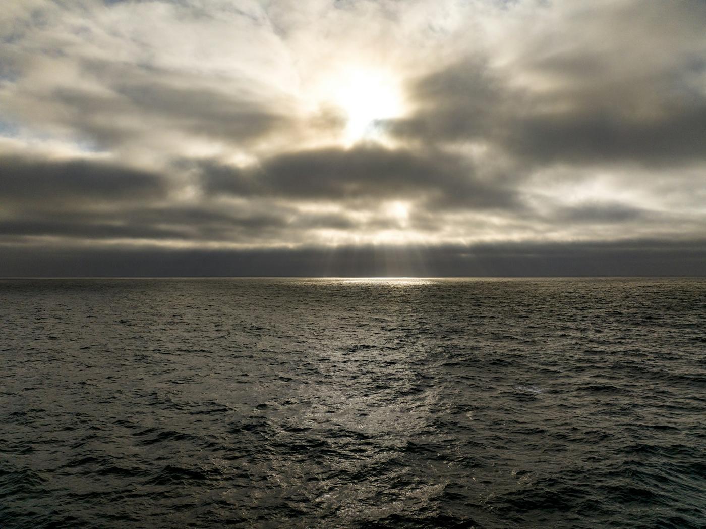 Sol velado entre nubes sobre el mar