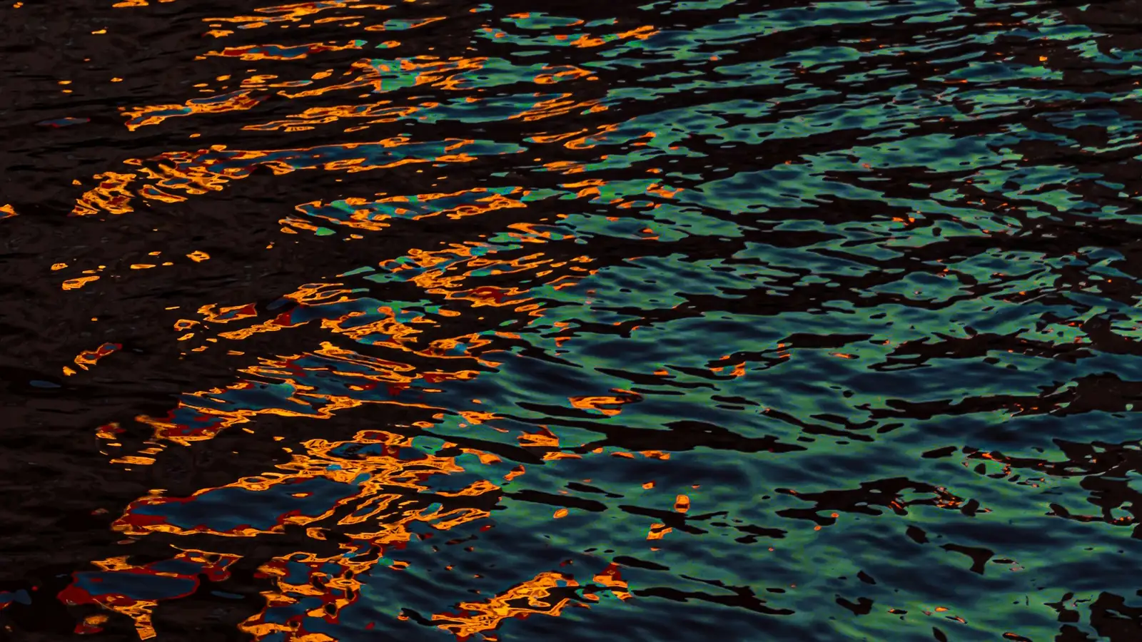 Reflejos naranjas sobre agua azul oscura