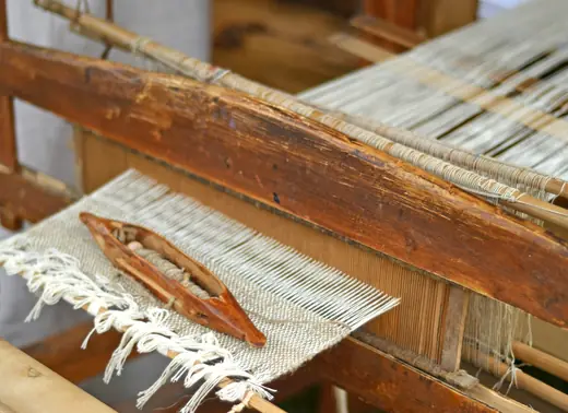 Telar antiguo de madera con una lanzadera sobre la trama