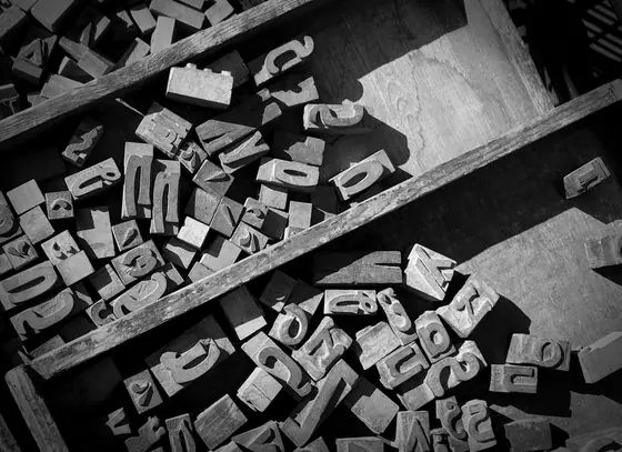 Letras de imprenta de plomo, sueltas sobre una mesa, en blanco y negro
