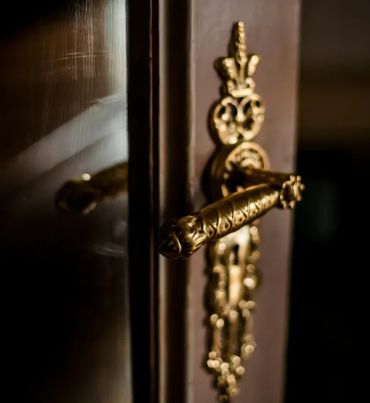Picaporte antiguo de bronce con adornos sobre una puerta oscura