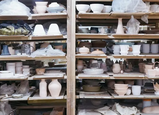 Estantes de madera llenos de piezas de cerámica en un taller
