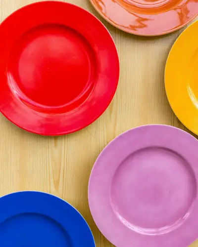 Platos rojos, rosados y azules sobre una mesa de madera