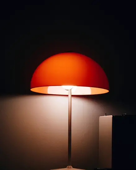 Lámpara de mesa de pantalla anaranjada que brilla en la penumbra