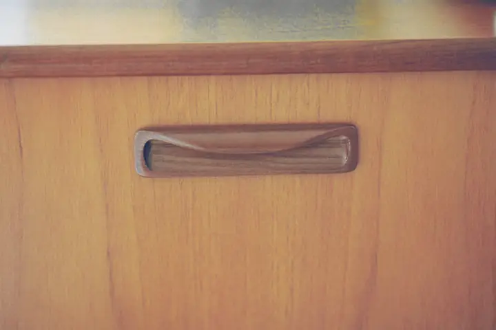 Tirador embutido en la puerta de un mueble de madera