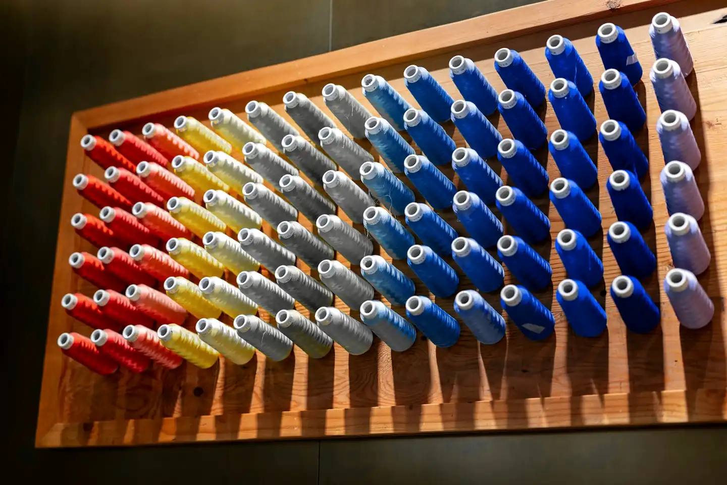 Tablero de madera con carretes de hilo ordenados por color