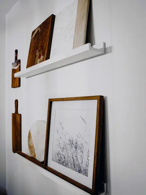 Repisa blanca con cuadros apoyados en la pared