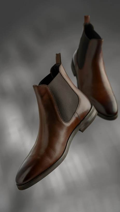 Botines de cuero marrón con elástico lateral, suspendidos en el aire