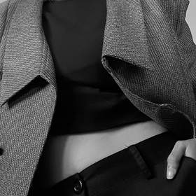 Chaqueta de tweed sobre una blusa negra, sin rostro, en blanco y negro