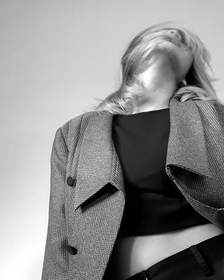 Chaqueta de tweed sobre una blusa negra, sin rostro, en blanco y negro