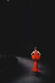 Figura de rojo al fondo de una pasarela oscura