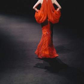 Figura de rojo al fondo de una pasarela oscura