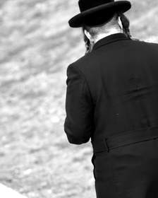Figura de espaldas con sombrero y abrigo largo, en blanco y negro