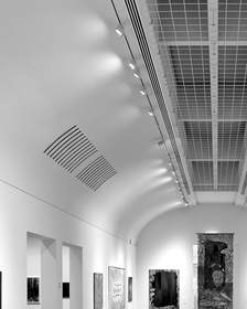 Sala larga de un museo con suelo de madera y obras en las paredes