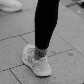 Piernas y zapatillas sobre baldosas grises