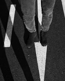Pies que cruzan una calle con franjas de sombra