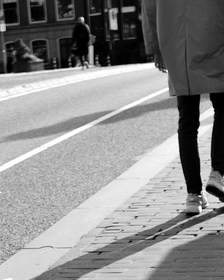 Dos figuras que caminan con sombras largas por una calle de adoquines