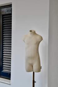 Torso de maniquí crudo junto a una pared blanca