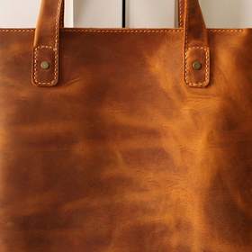 Bolso de cuero caramelo colgado de una puerta blanca