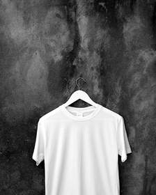 Camiseta blanca colgada de una percha sobre una pared de cemento