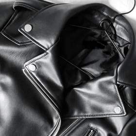 Chaqueta de cuero negro con cierre diagonal sobre una tela blanca