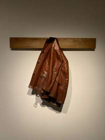 Chaqueta de cuero marrón colgada de un riel de madera